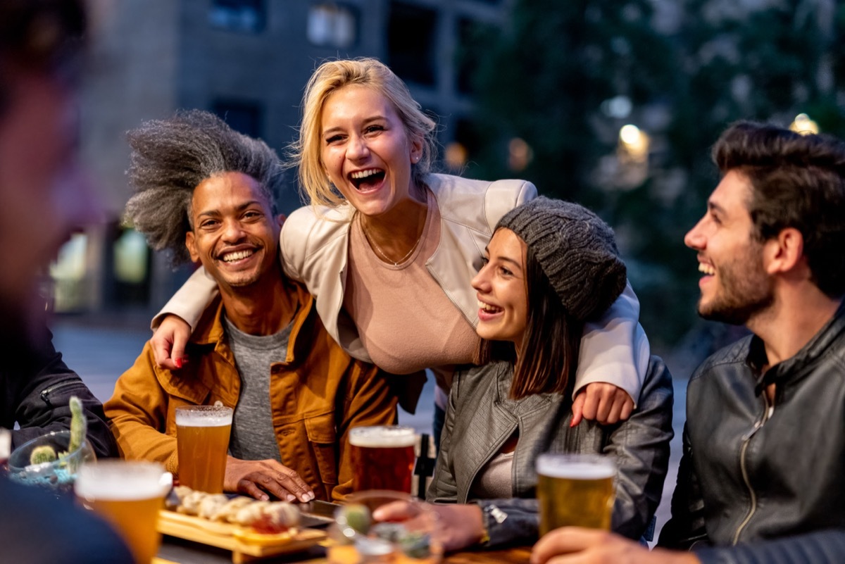 group of friends laughing and exchanging anti-jokes while at a bar