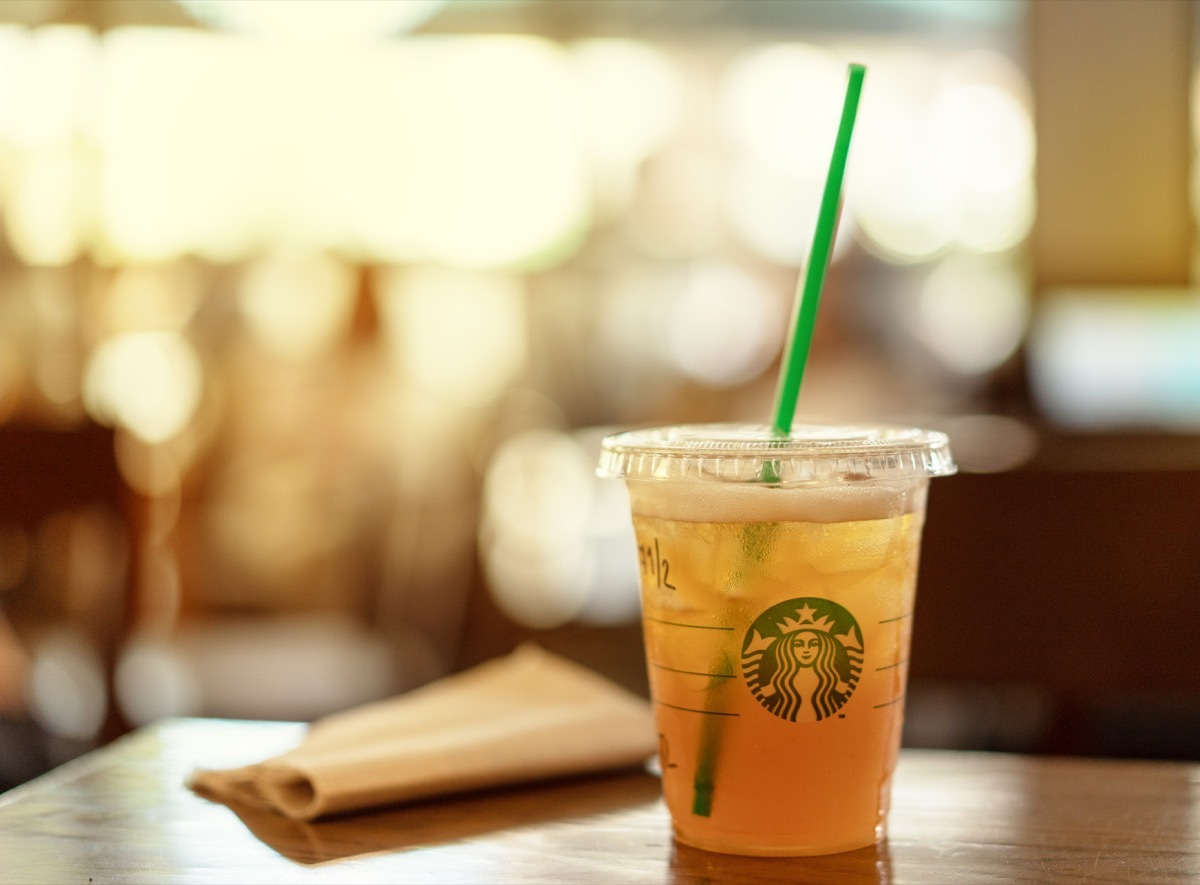 BANGKOK, THAILAND - JUNE 22,2018 : Starbucks iced lemon tea on a wooden table in Starbucks coffee shop with brown napkin paper.