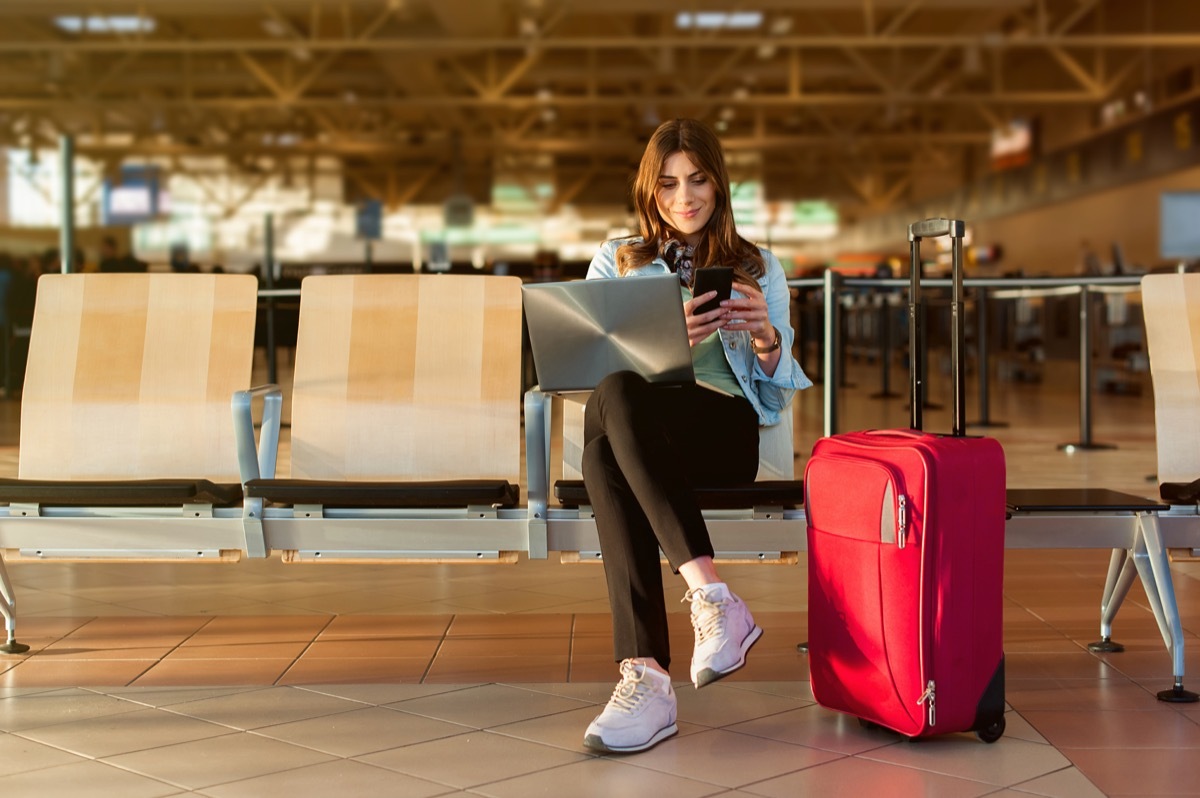 Woman Sitting at the Airport Waiting to Travel booking cheap flights
