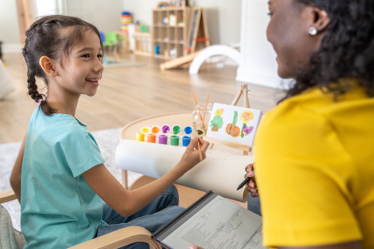 A female art therapist works with a young female child