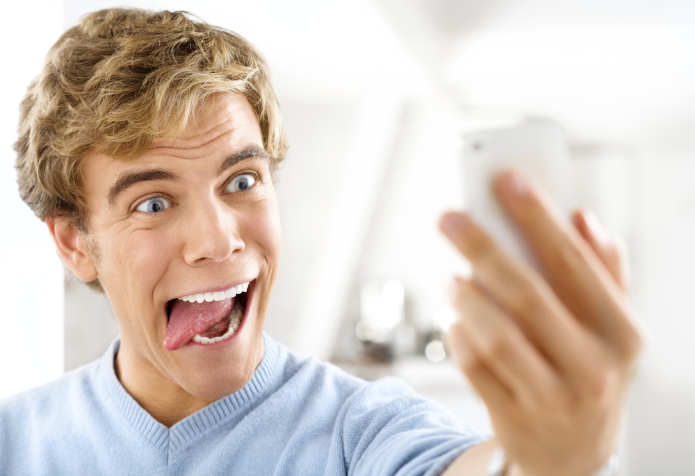Attractive young man taking self portrait using mobile phone