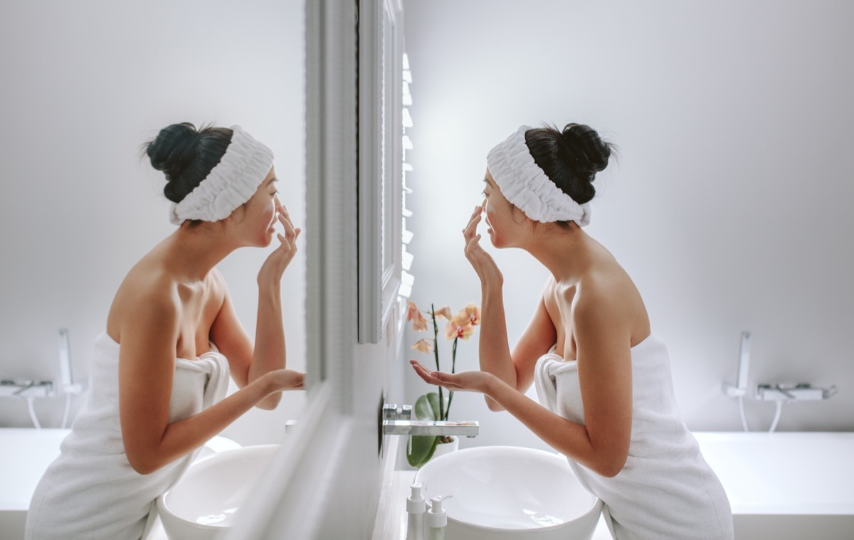 Woman applying cream in bathroom