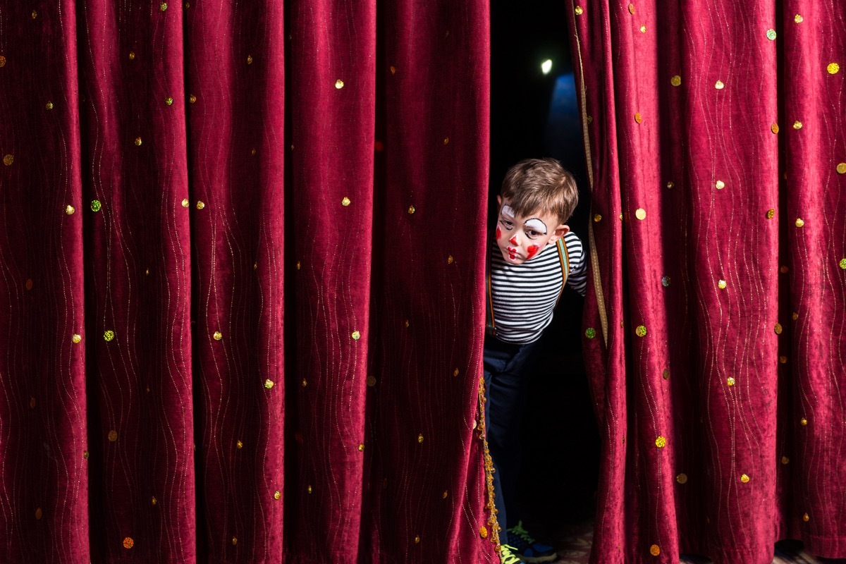 boy peeking through stage curtains