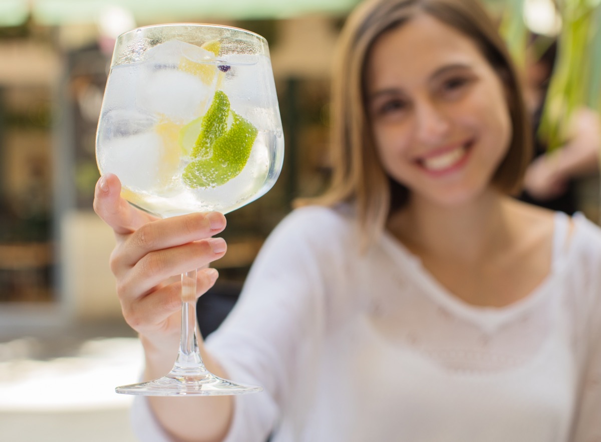 young woman holding drink, gin and tonic, in glass