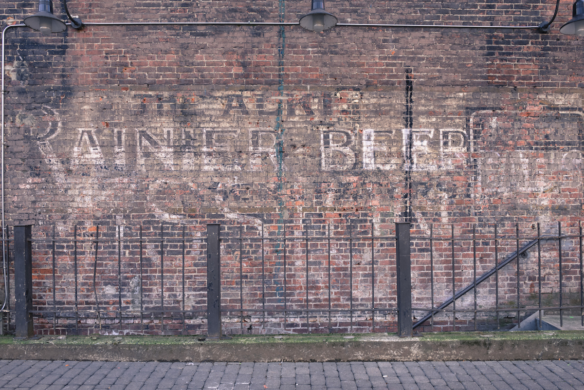 An old Historic Alki Rainier Beer advertising sign on a brick wall in Occidental park in the historic Pioneer Square neighborhood.