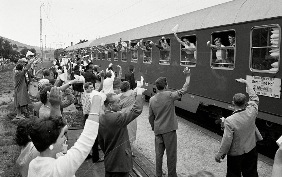 a group of people wave at train passengers