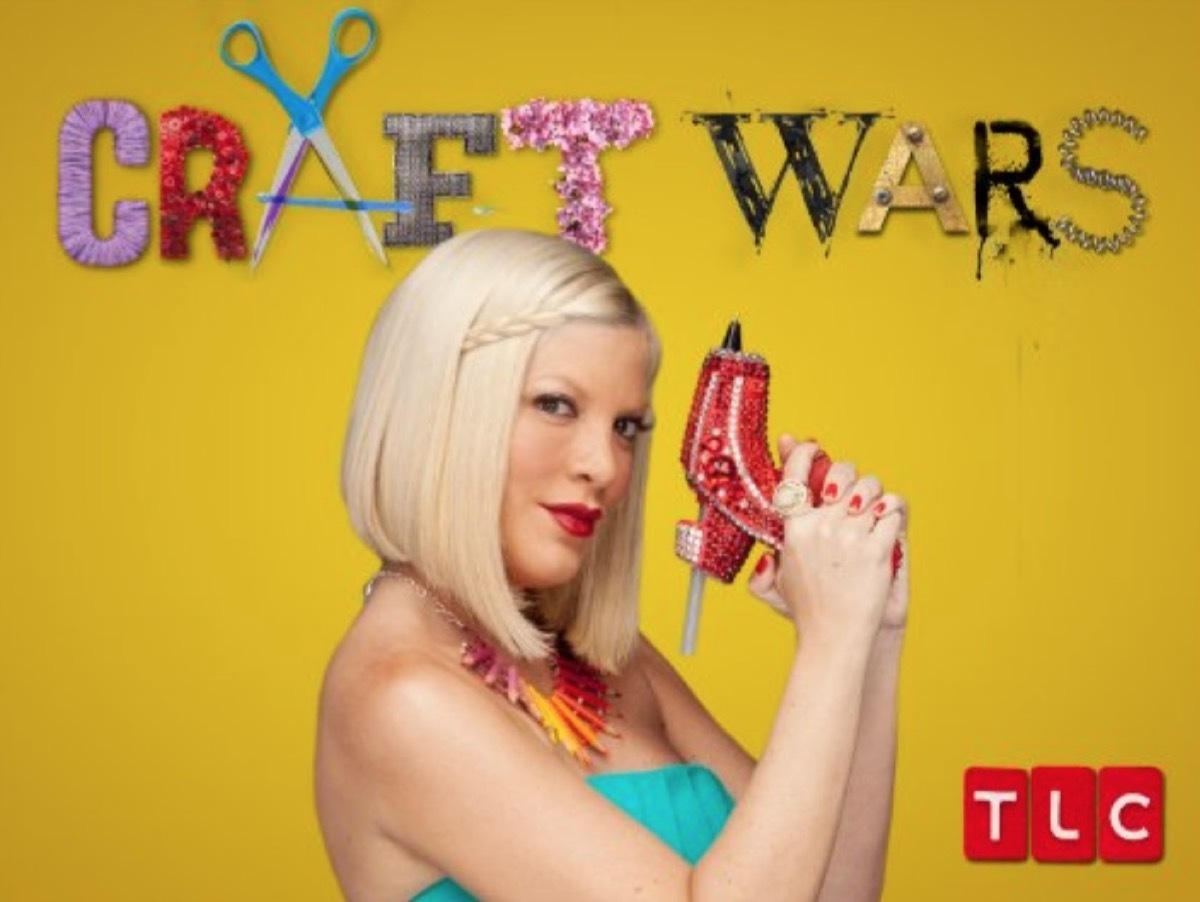 tori spelling holding red glue gun in front of yellow background