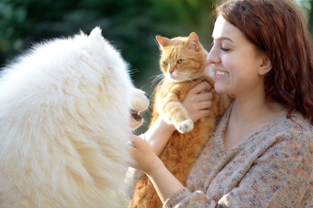 Woman holding her cat and hanging out with her fluffy dog