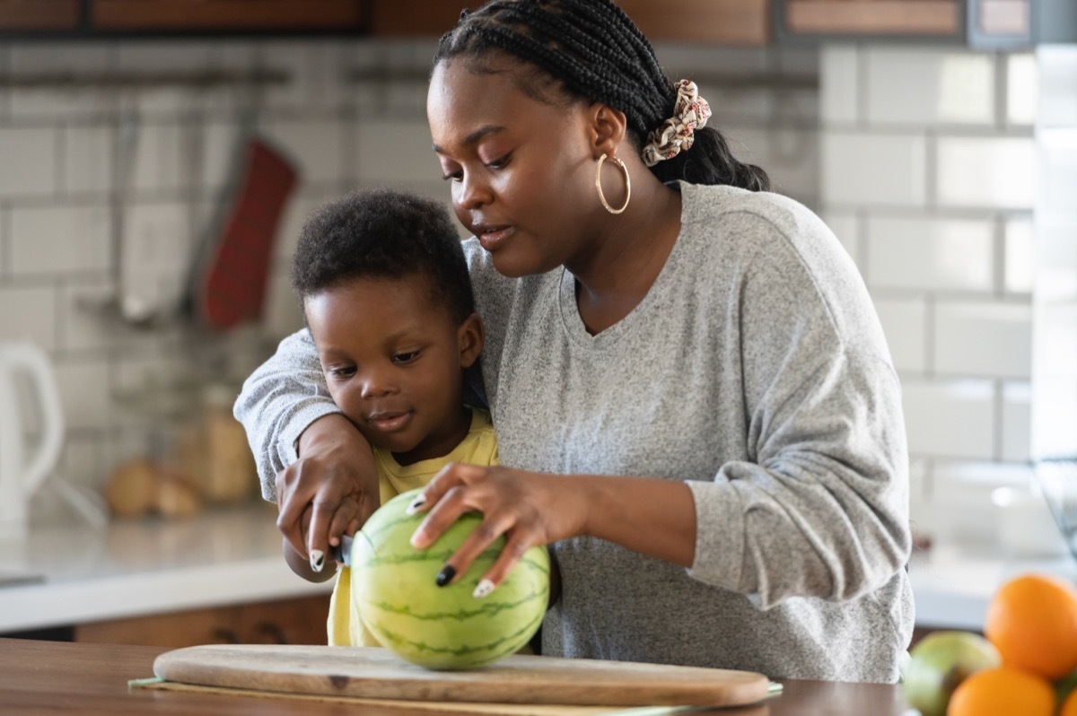 Mother and son cutting whole watermelon