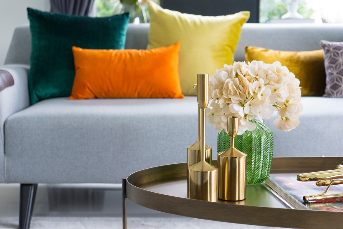 gold vases and flowers on table in front of sofa