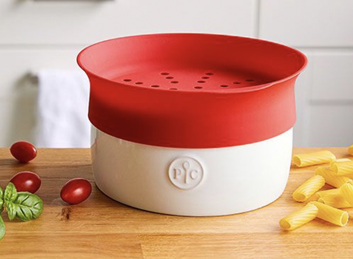 red and white microwave pasta cooker next to cherry tomato on butcher block counter