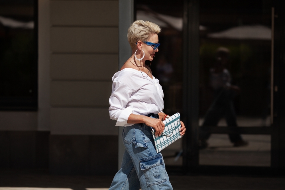 Fashionable older woman with short hair, denim cargo pants, and clutch