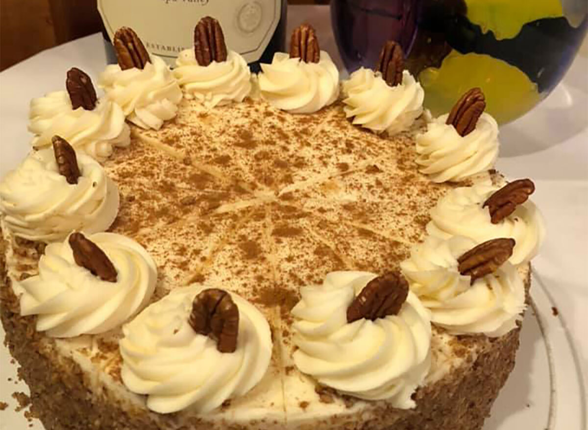 whole carrot cake topped with whipped cream and pecans