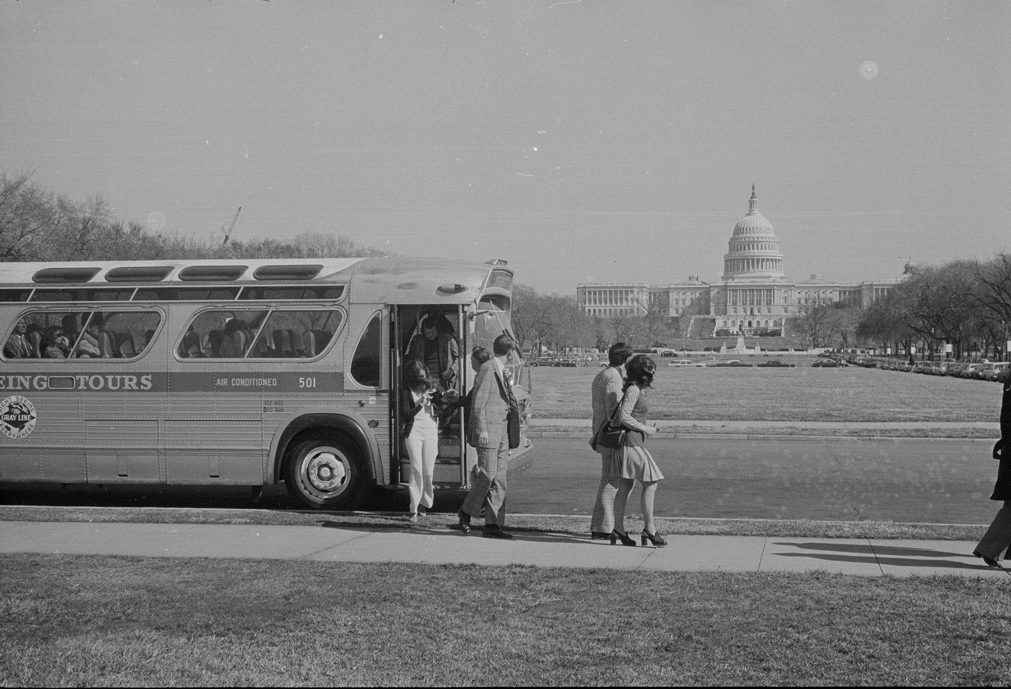 a group of people get off a bus in front of capitol hill