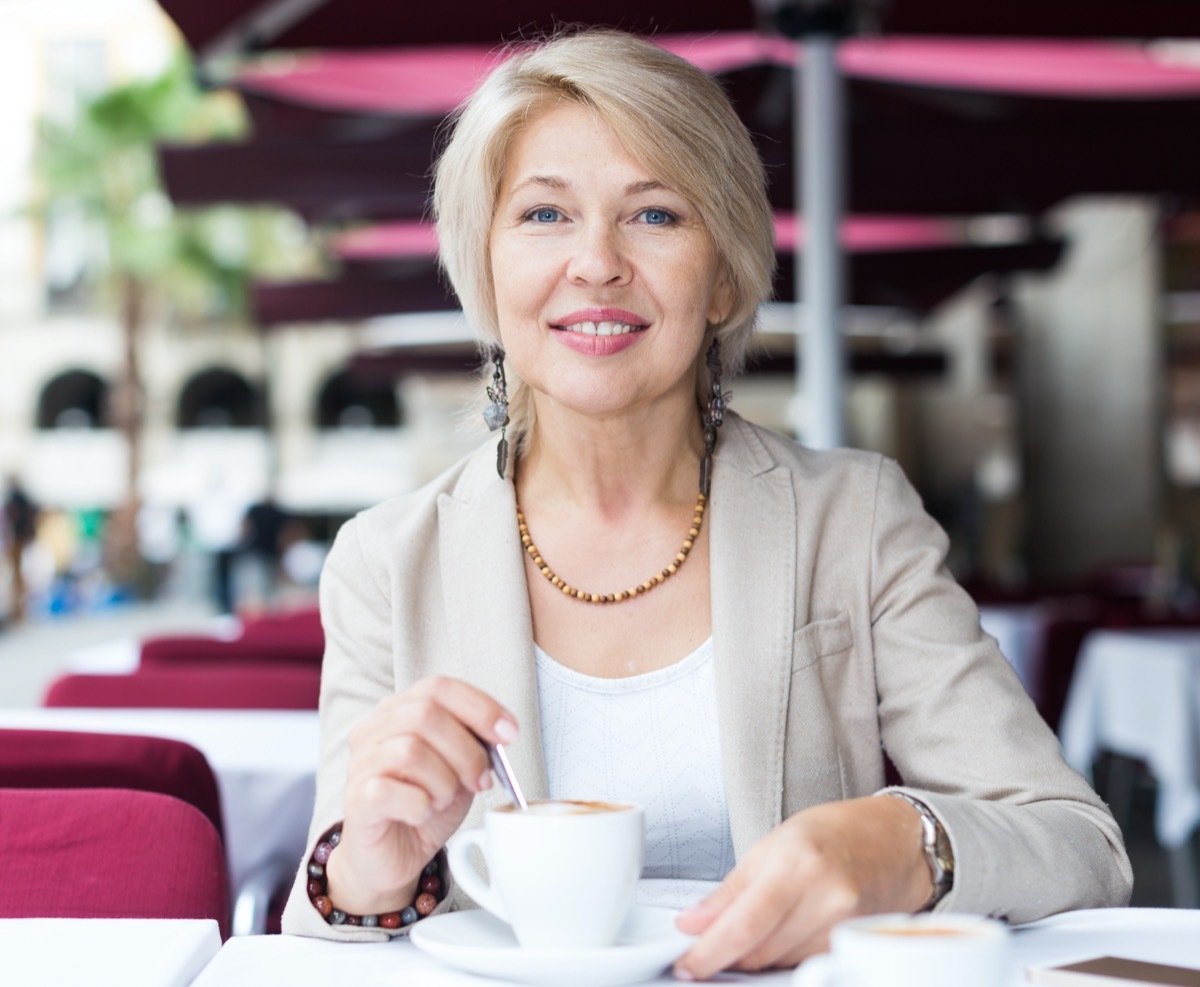 mature female who is enjoying of lunch with coffee in cafe