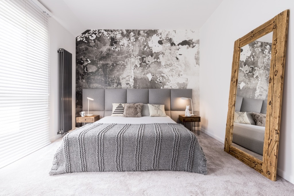 small well designed monochromatic modern bedroom with a wooden mirror against the wall