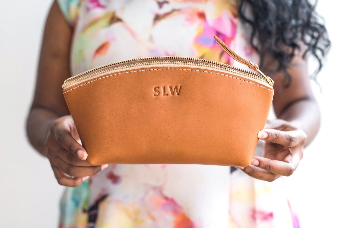 woman holding leather makeup case with monogram