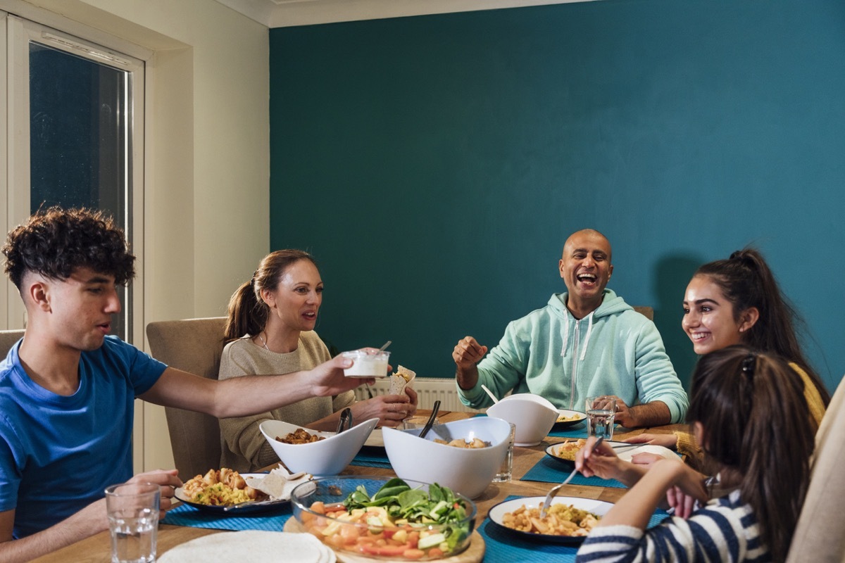 A family of five sitting at the table in their home in the North East of England enjoying a family meal together and catching up as a family over dinner.