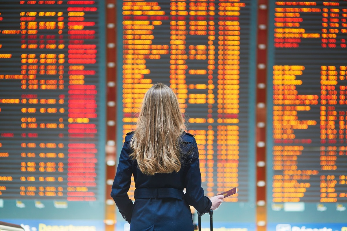 Woman standing in front of departures board at airport