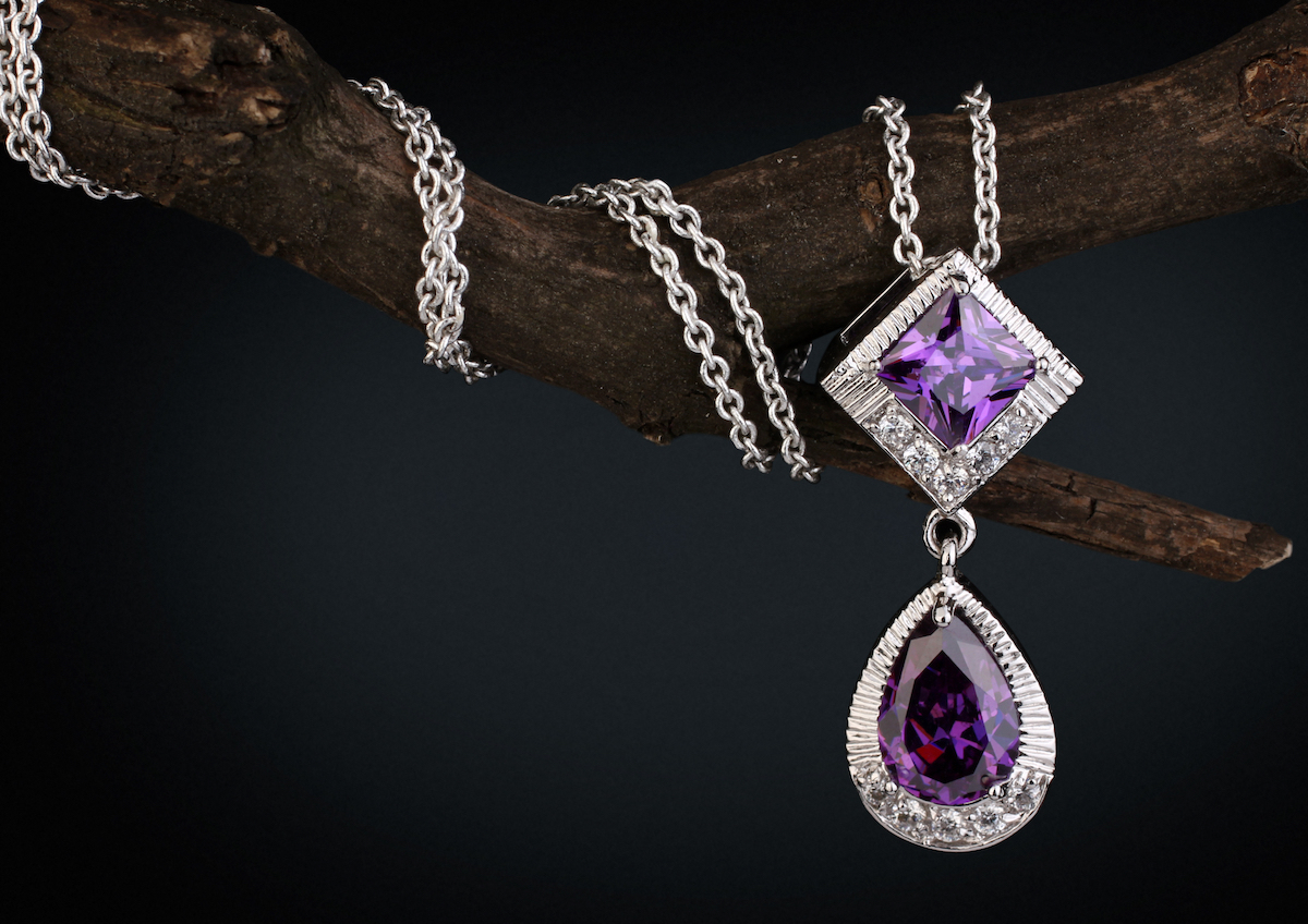 An amethyst necklace wrapped around a branch on a black background