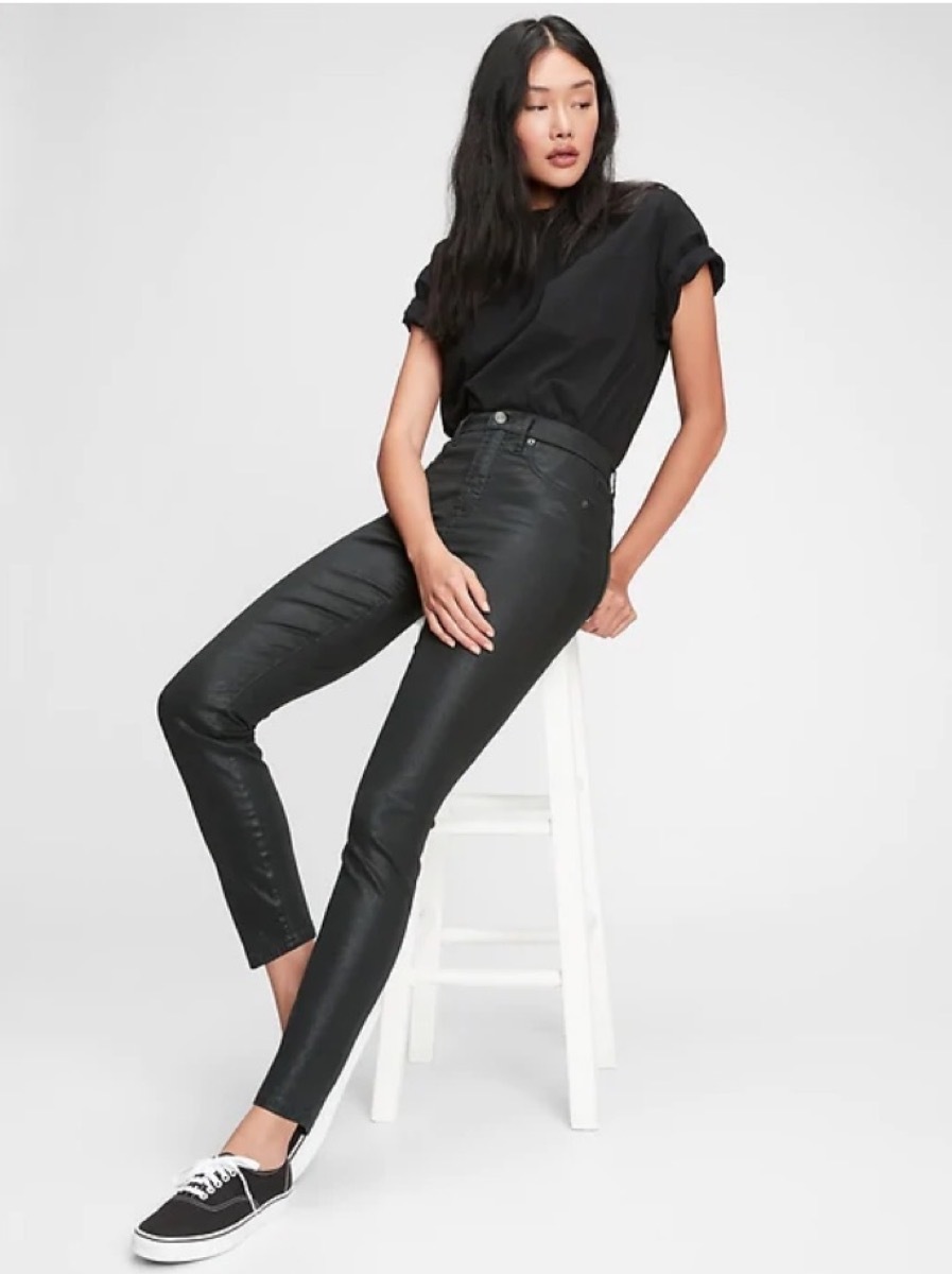 young woman sitting on stool wearing cropped jeans and black shirt