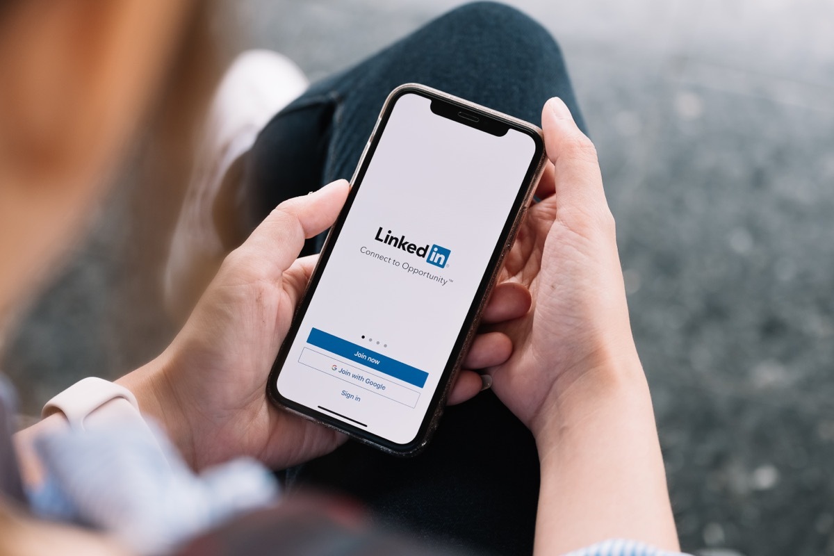 close up of hands holding a phone screen showing linkedin