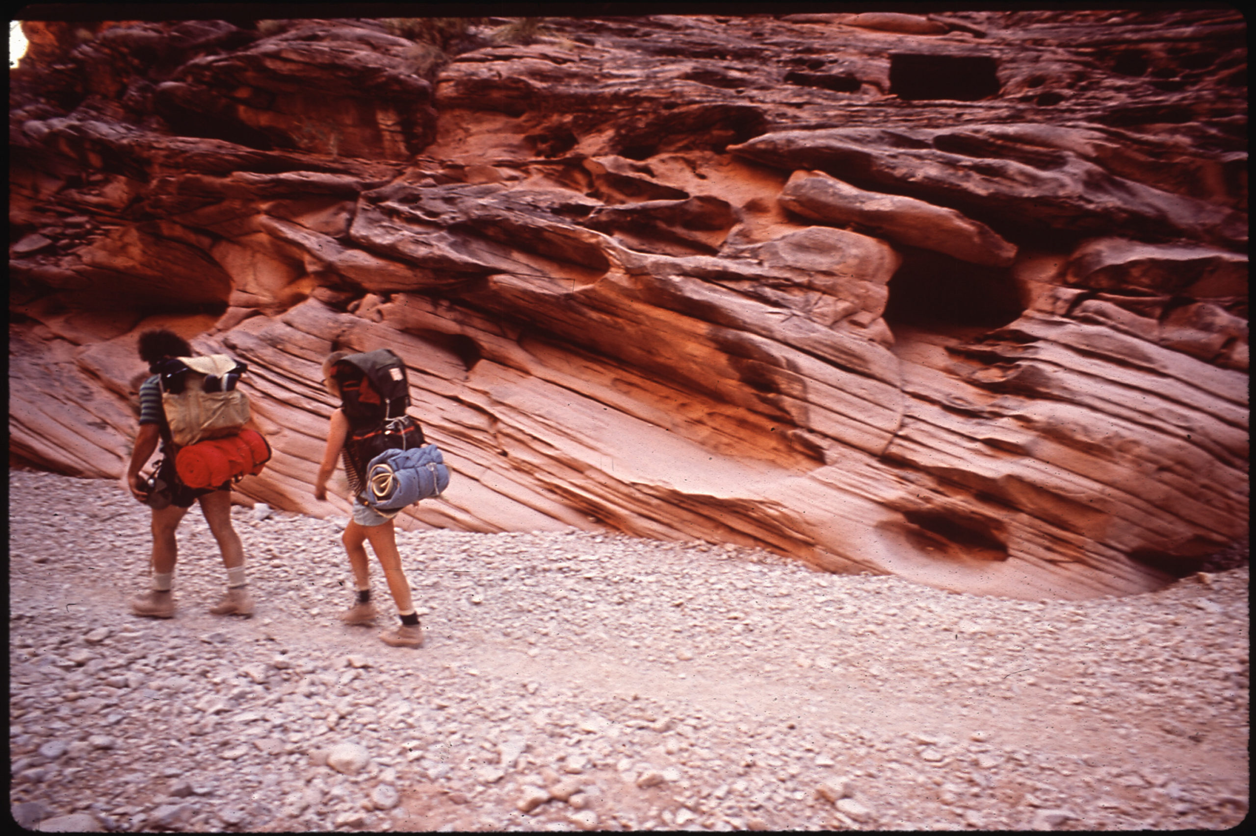two hikers walk through a canyon