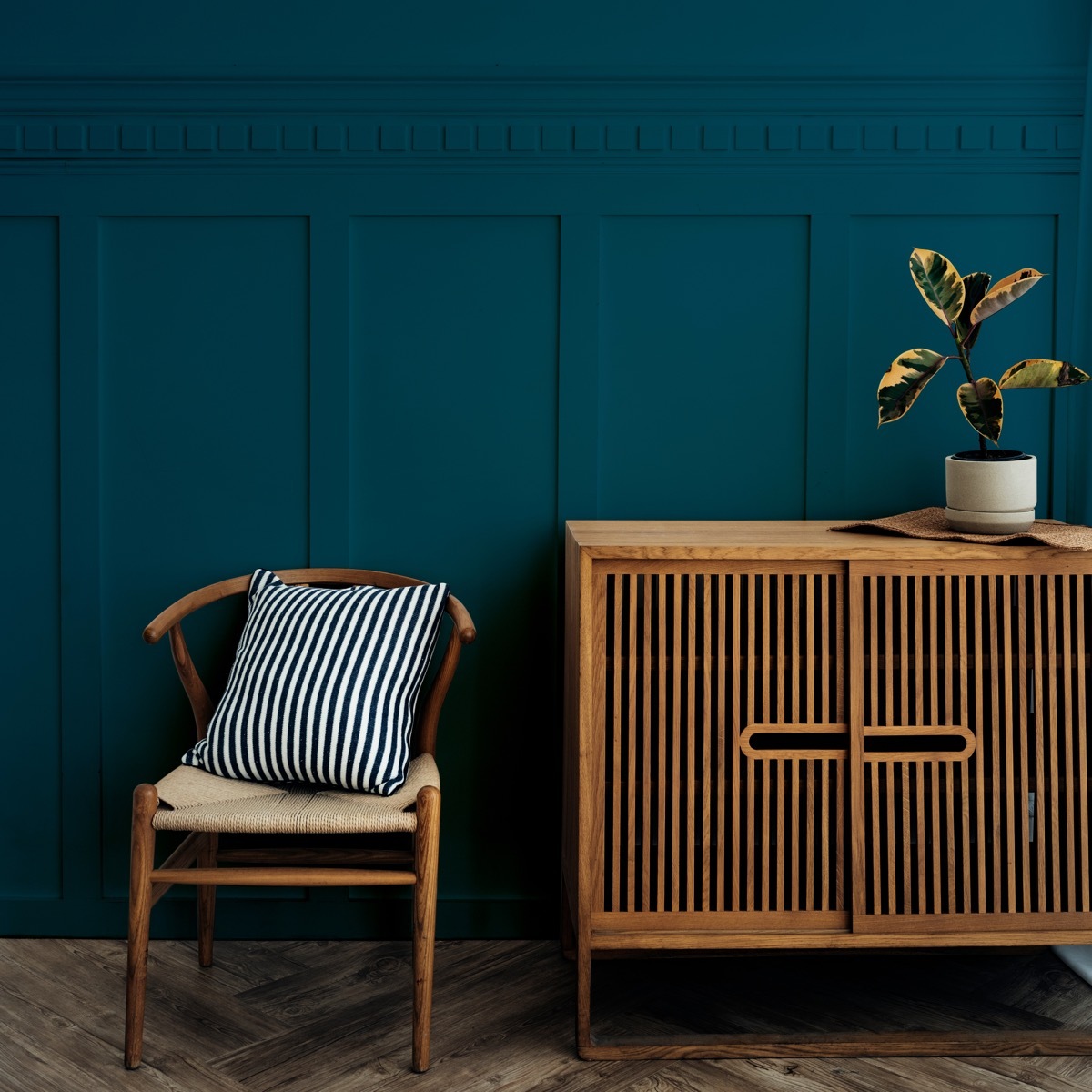 Scandinavian vintage wood cabinet with chair by a dark blue wall