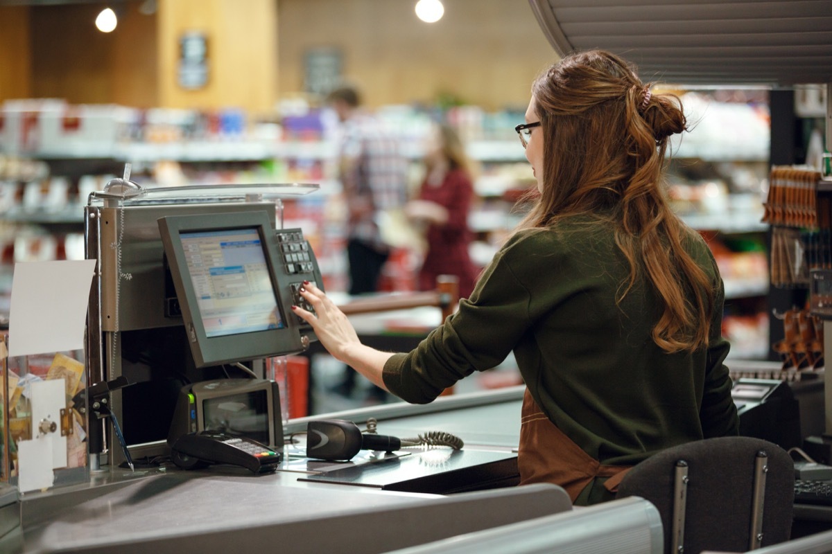 young white woman operating cash register at grocery store