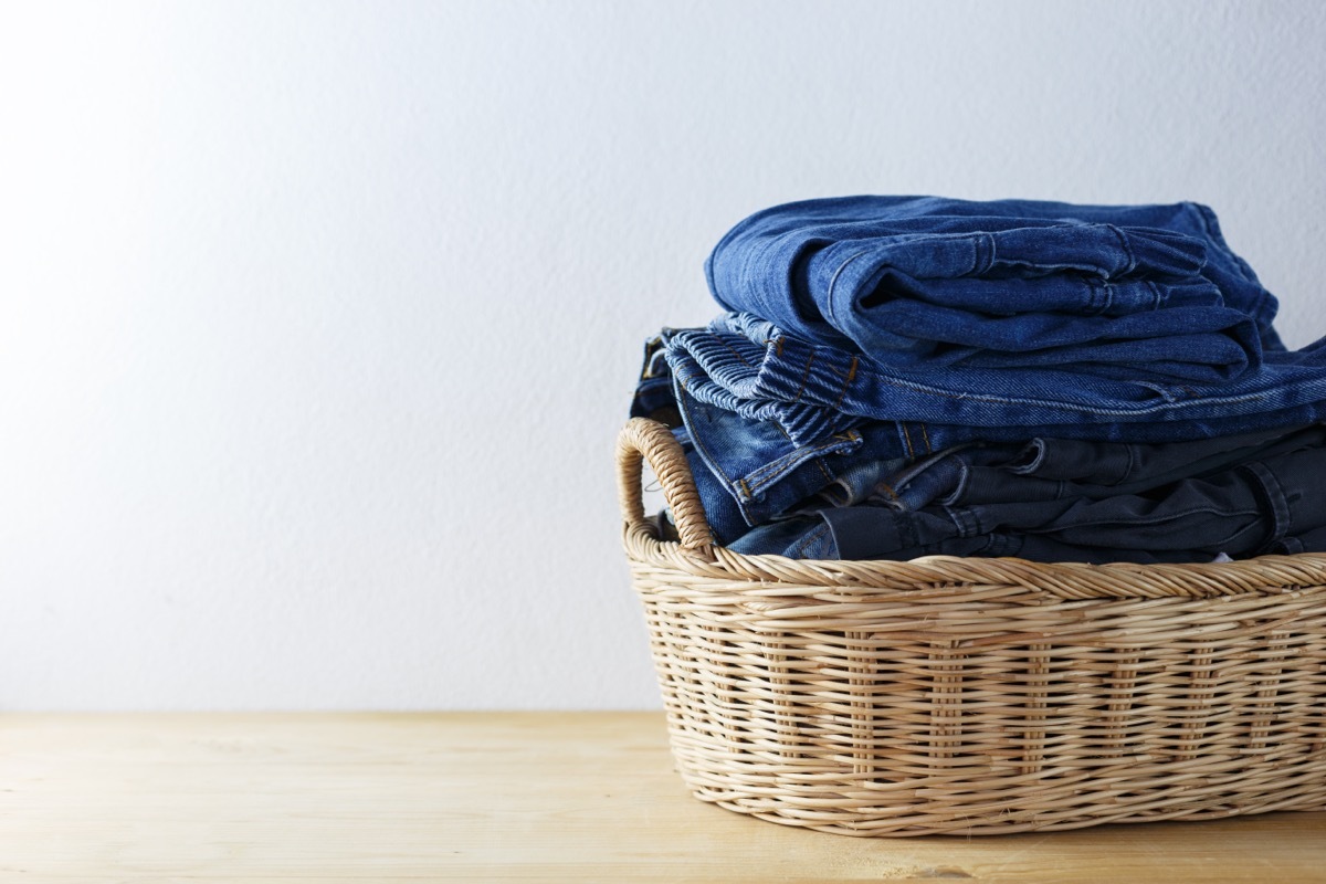 Clothes and jeans in a laundry basket on Wood floor