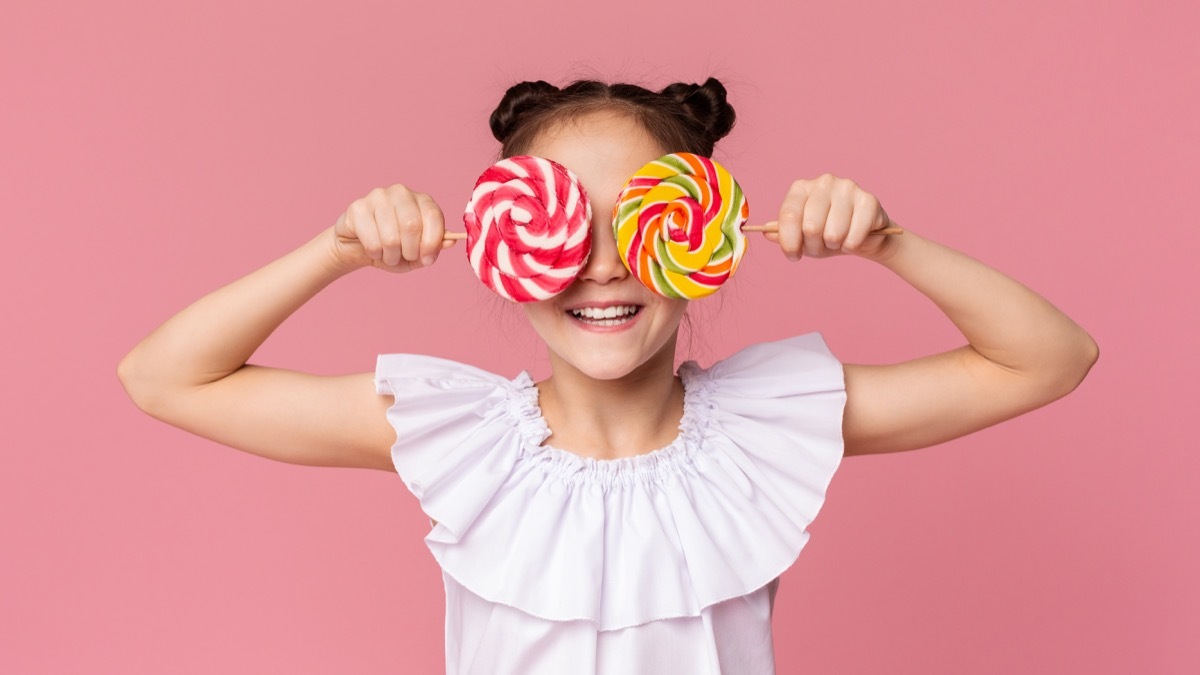 little girl holding two lollipops