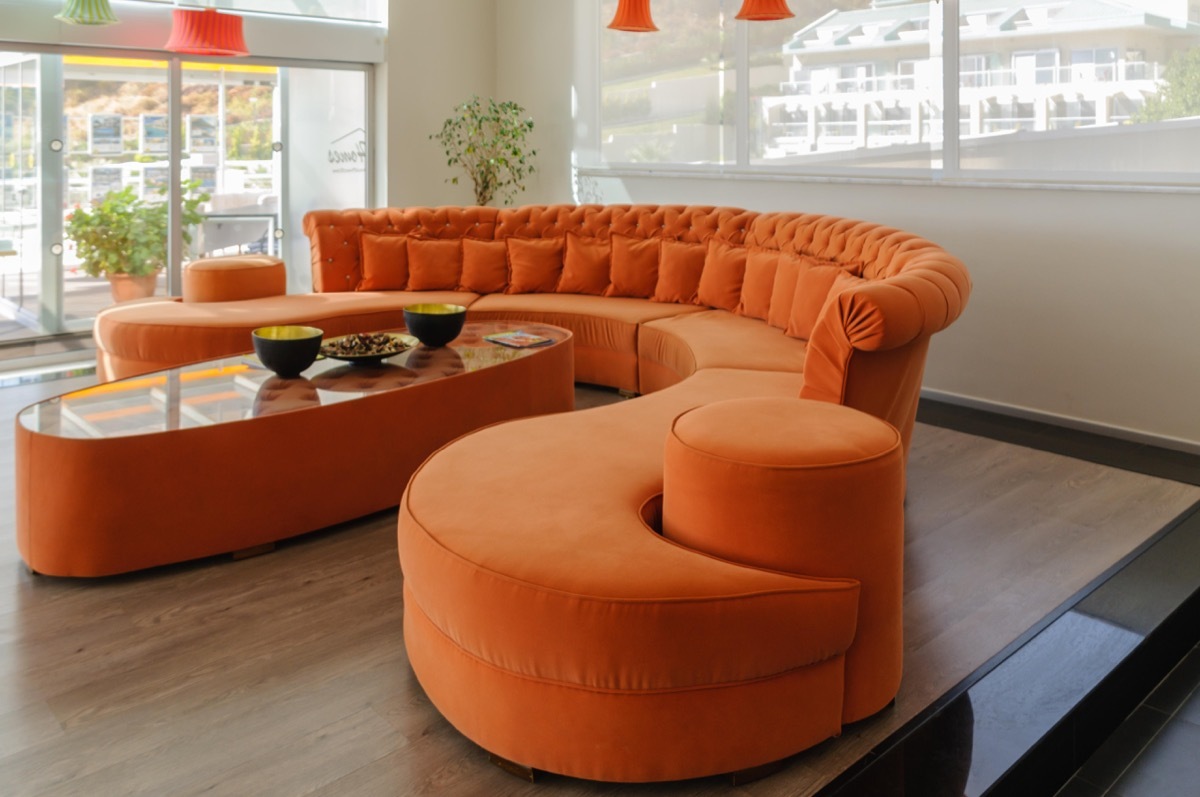 PRCJ5W Orange curved sofa and table in a large, modern, contemporary room.