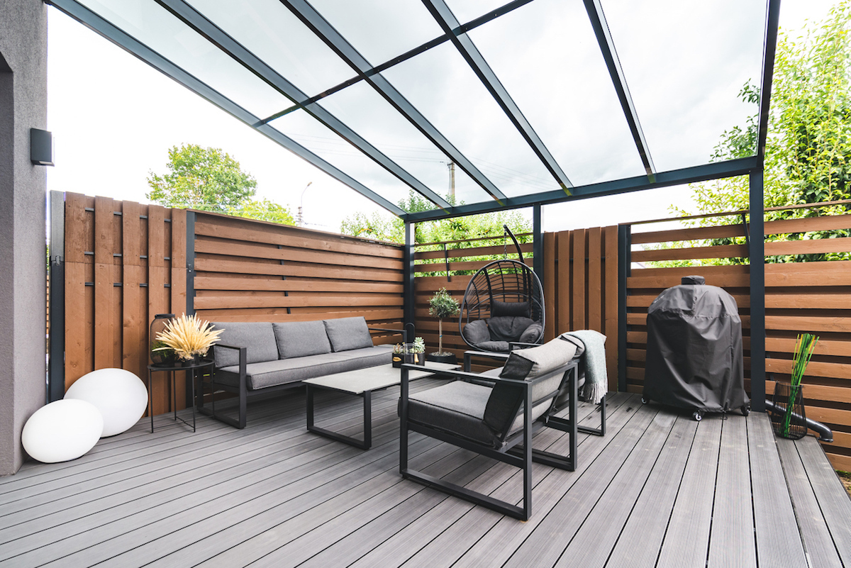 Outdoor terrace with a comfortable outdoor sofa and chairs next to a private building.