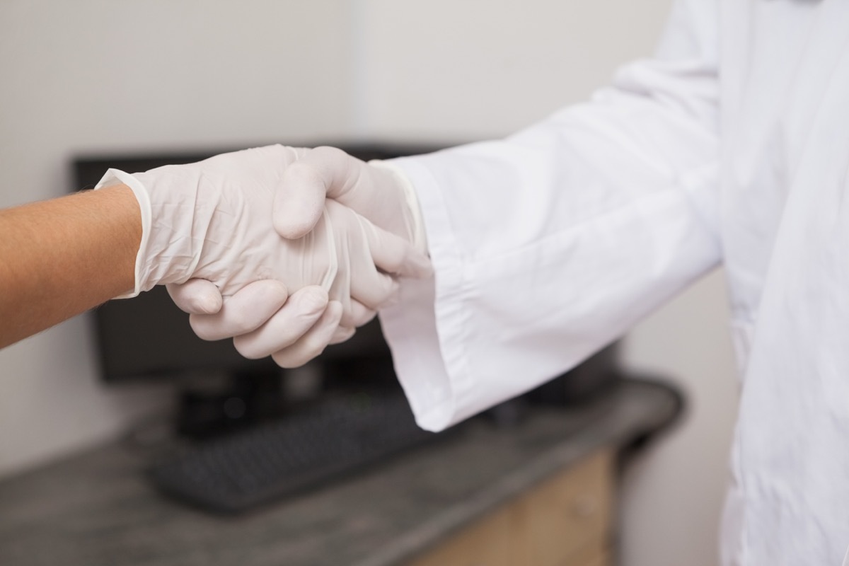 two people shaking hands while wearing gloves