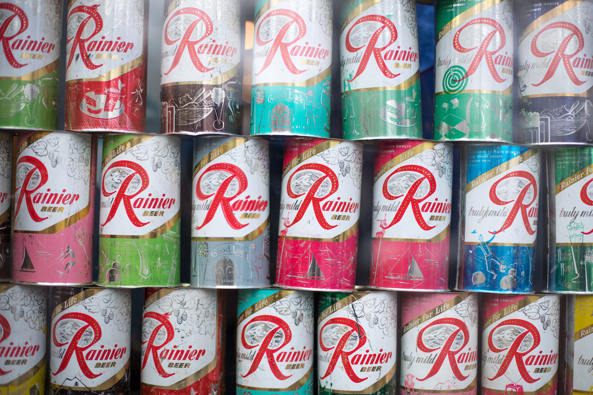 Display of vintage Rainier Beer cans, in an antique food background