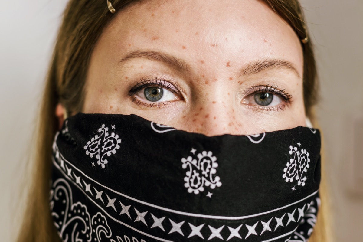 woman with freckles wearing black bandana face mask