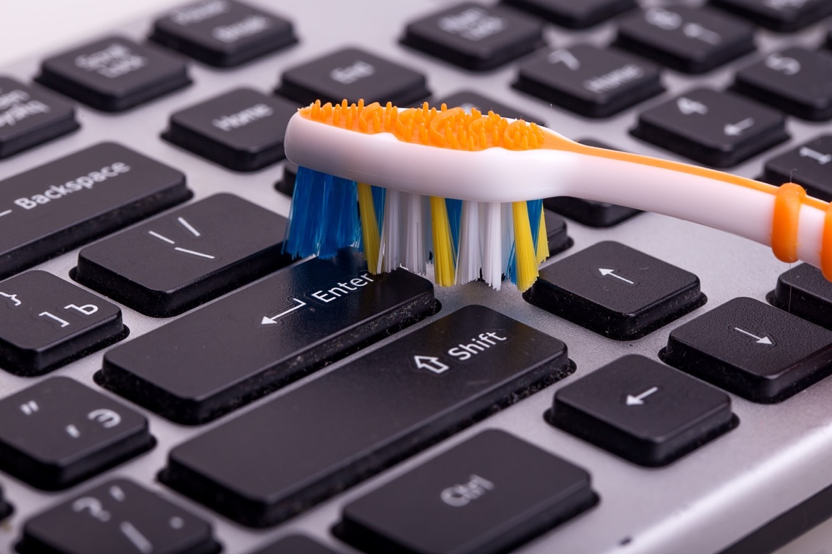 Person Cleaning a Keyboard with a Toothbrush Cleaning Hacks