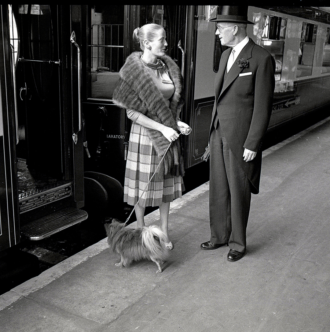 a train maitre d' talks to a woman and her dog
