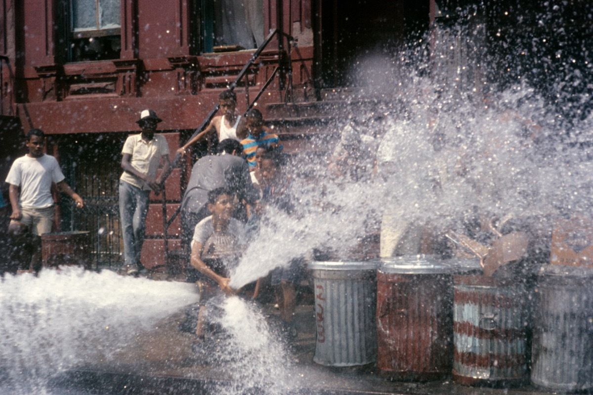 Kids play in water from hydrant in street 1980s