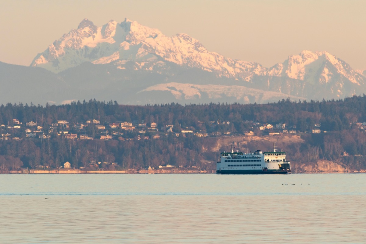 seattle ferry floats in the bay with snowy mountains behind it
