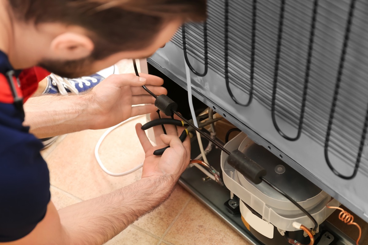 man cleaning refrigerator coil