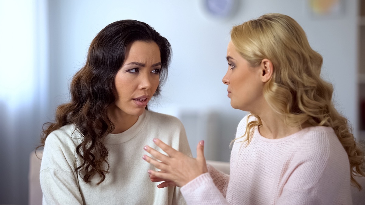 30-something asian woman looking concerned while talking to blonde woman