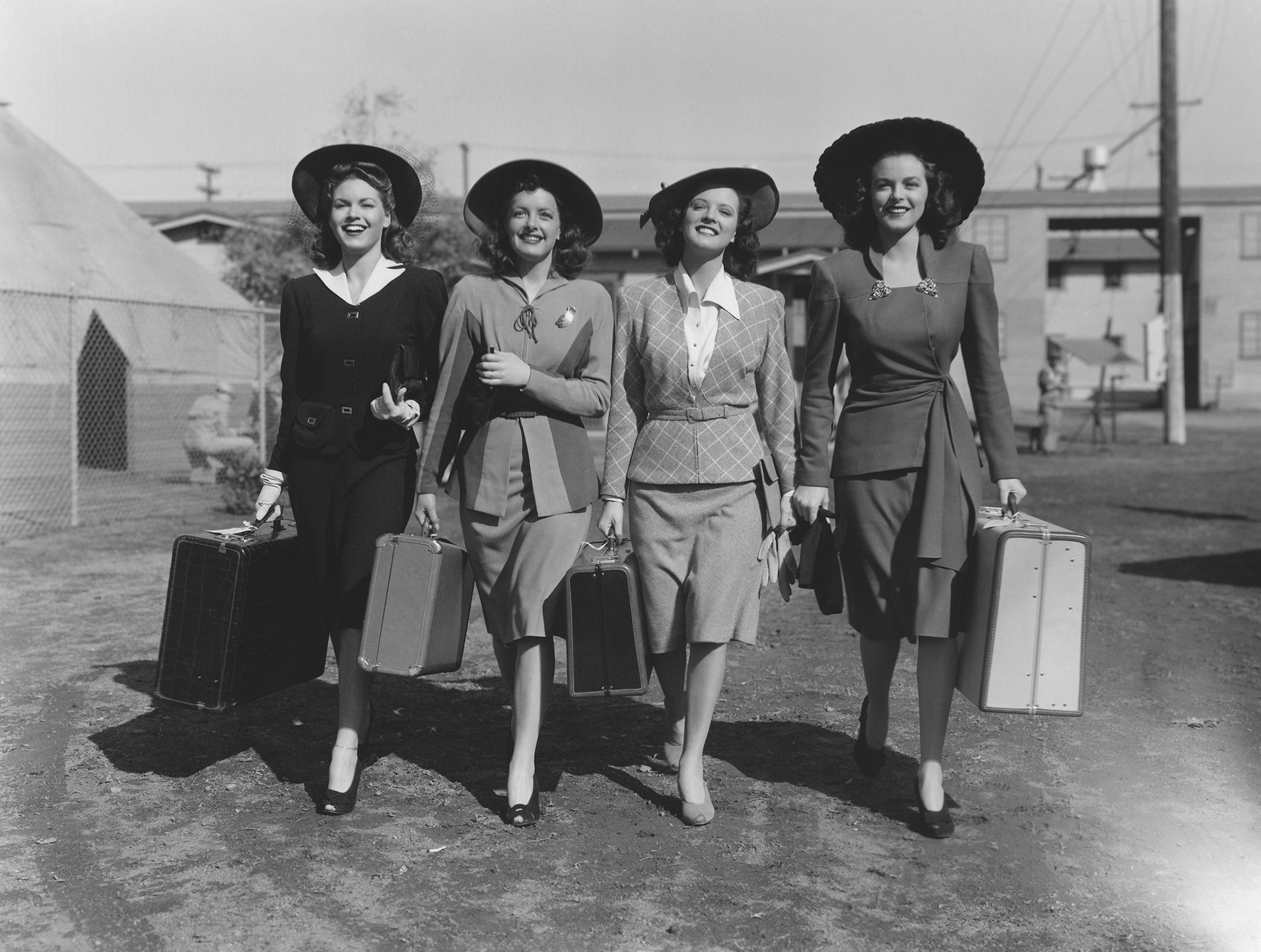 four women walk with suitcases