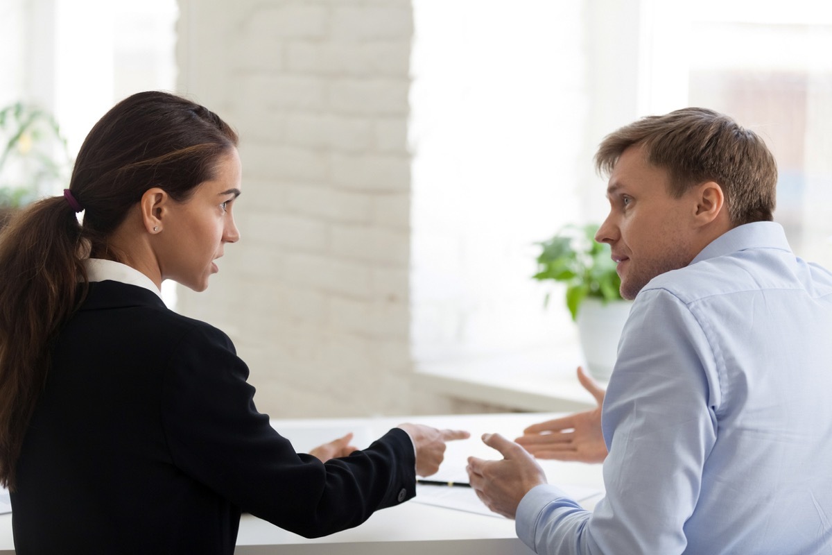 white woman at work pointing a finger at shrugging white male coworker