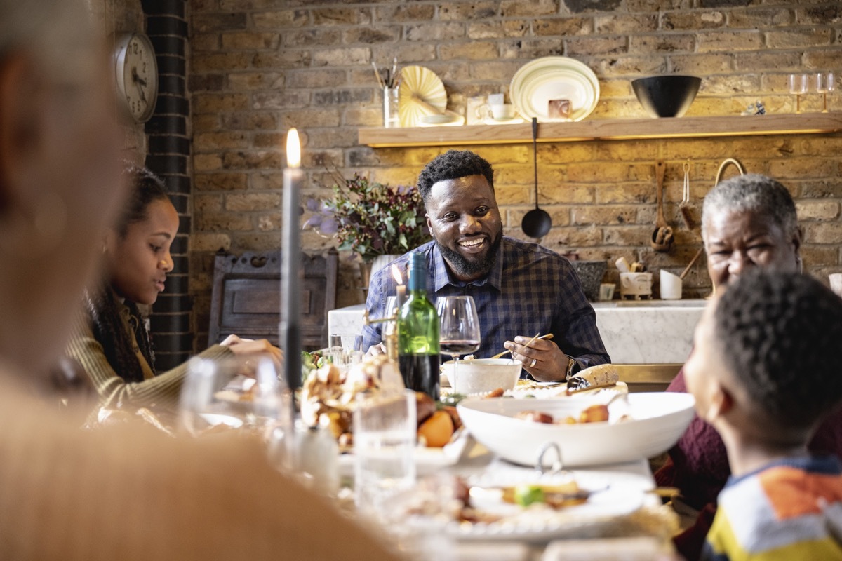 family seated listening to child telling story at dinner table