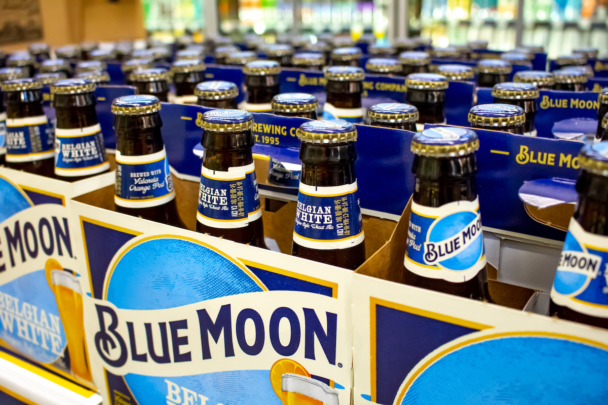 Several six pack cases of Blue Moon beer on a shelf at a grocery store