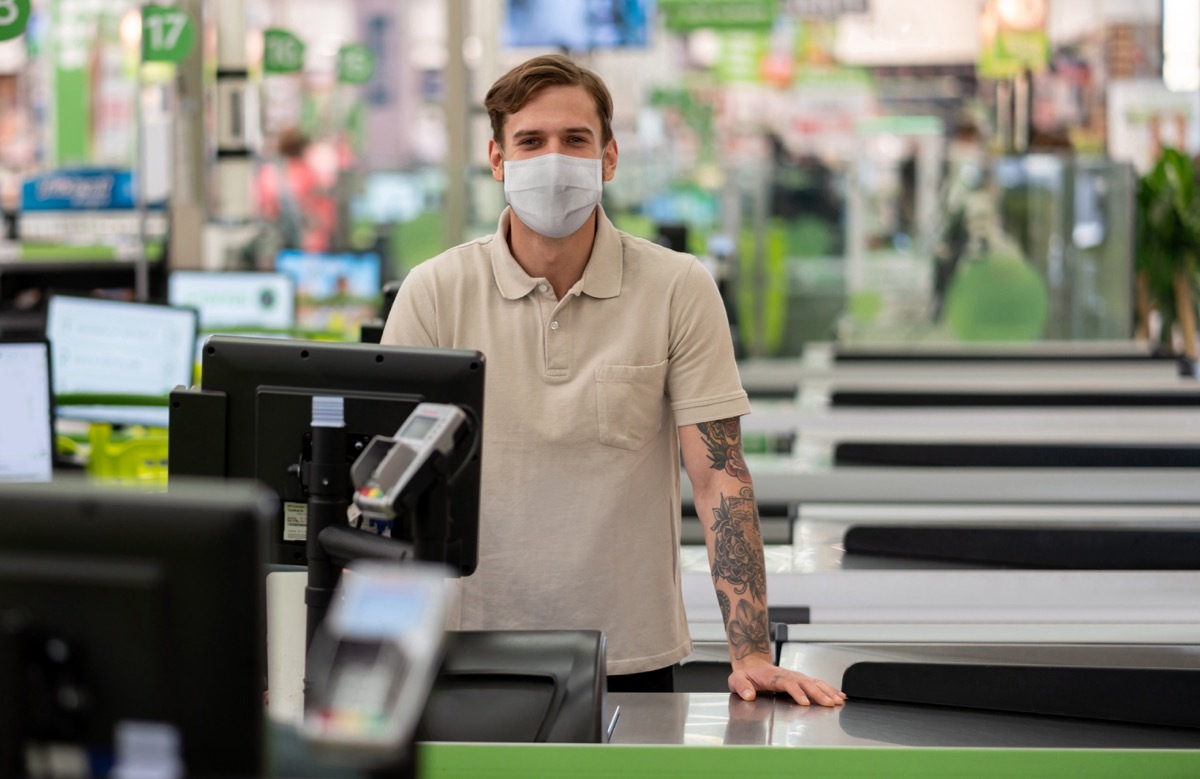cashier working at a supermarket wearing a facemask during the COVID-19 pandemic