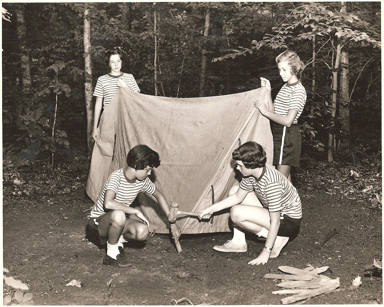 three girls set up a tent in the woods