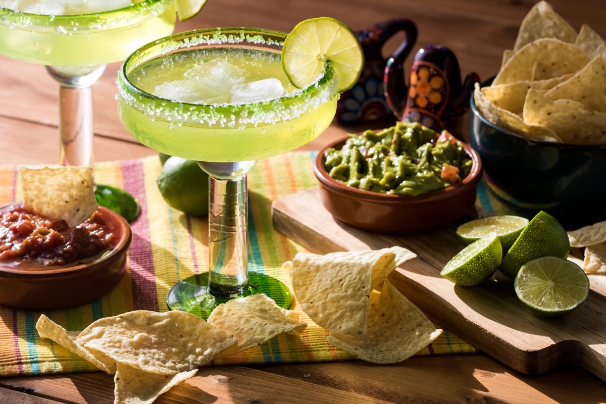 margarita in glass, salt on rim, guacamole and chips on table