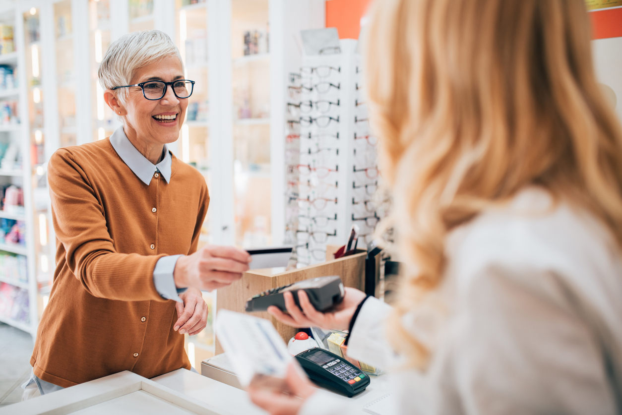 A senior woman making a purchase at a pharmacy